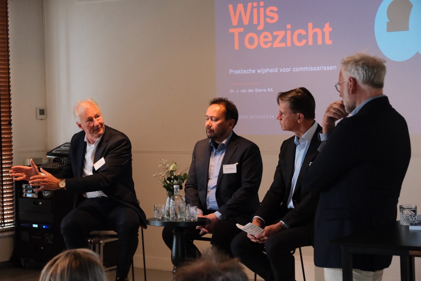 Drie mannen op podium in gesprek, zakelijke reportagefotografie
