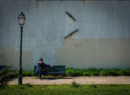 Man op bankje voor verweerde muur, straatfotografie van der Starre Fotografie